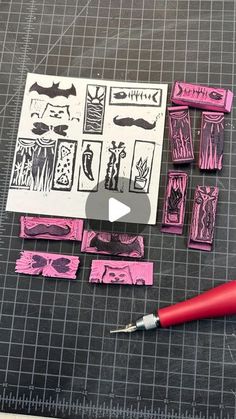 some pink and black stamps are laying on a piece of paper next to a red pen