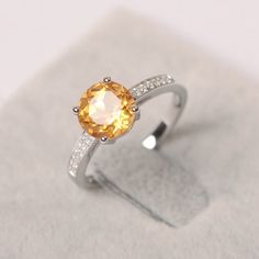 an orange and white diamond ring sitting on top of a table