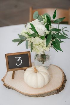 there is a vase with flowers and a chalkboard on the wooden stand next to it