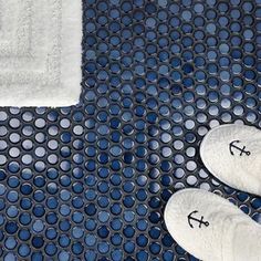 two pairs of feet in white slippers standing on a blue and black floor mat