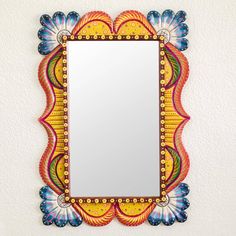 a colorful mirror hanging on the wall with an ornate frame and decorative decorations around it