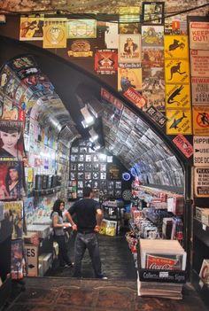 two people standing in the middle of a store with posters on the walls and ceiling