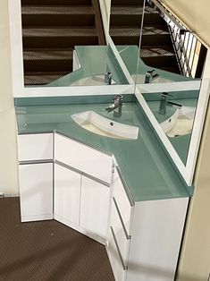 a bathroom vanity with two sinks under a large mirror and stairs leading up to the second floor