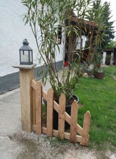 a wooden fence with a lantern on top and a tree in the middle next to it