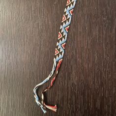 a braided lanyard on a wooden surface with an orange, white and blue design