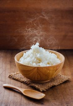 a wooden bowl filled with rice on top of a table