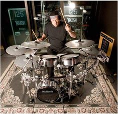 a man sitting in front of a drum set on top of a carpeted floor