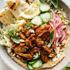 a bowl filled with meat, vegetables and pita bread on top of a table