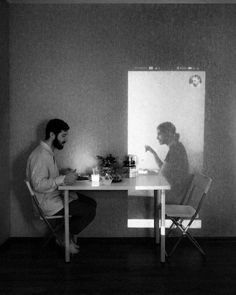 two people sitting at a table in front of a white board with the image of a man and woman on it