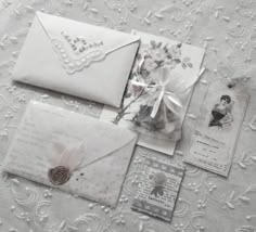 an assortment of cards and envelopes on a lace tablecloth with pink flowers in the center