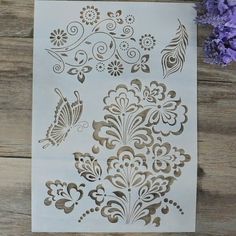 some paper cut outs with flowers and butterflies in them on a wooden table next to purple flowers