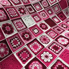 a pink and white crocheted blanket with hearts on it's sides, in the shape of squares