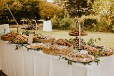 a table topped with lots of food on top of a white table cloth covered field