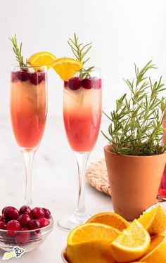 two wine glasses filled with cranberry lemonade and rosemary garnishes