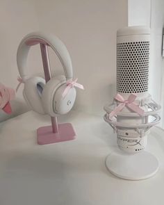 two white headphones are sitting on a stand next to a speaker and an air freshener