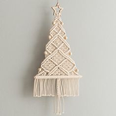 a small white christmas tree hanging from a hook on a wall with beads and tassels