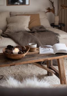 an open book is sitting on a table in front of a coffee table with a candle