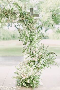 the cross is covered with flowers and greenery