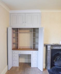 an empty room with a fireplace and built - in desk, cabinets, and bookshelves