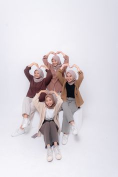 four women are posing for a photo with their hands up in the shape of hearts