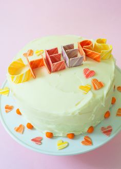 a white cake topped with lots of colorful icing hearts on top of a plate