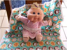 a baby doll sitting on top of a blanket