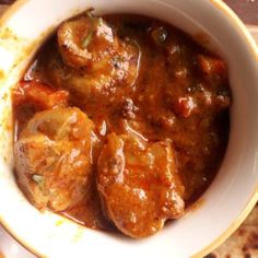 a bowl filled with meat and sauce on top of a table