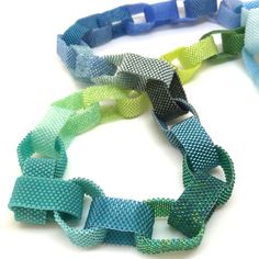 three different colored bracelets on a white surface, one is blue and the other is green