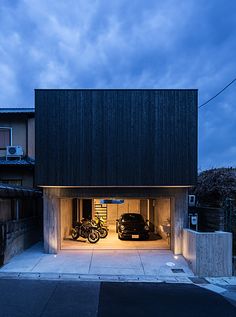 two motorcycles are parked in the garage at night, and one is on the other side