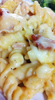 a plate with pasta, broccoli and bacon on it next to a fork