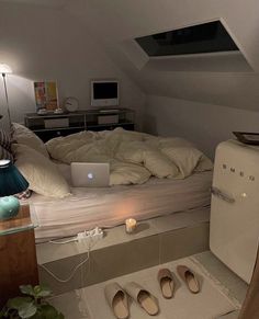 there is a laptop on the bed in this small room with white sheets and pillows