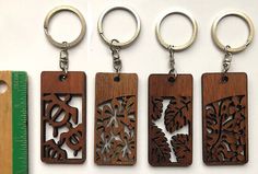 four wooden keychains with laser cut designs on them and a ruler in the foreground