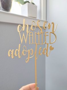 a person holding up a cake topper that says chosen wanted adopted