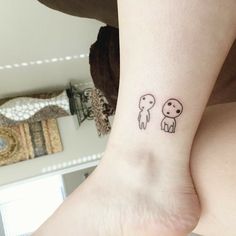 a small tattoo on the ankle of a woman's left foot, depicting two dogs