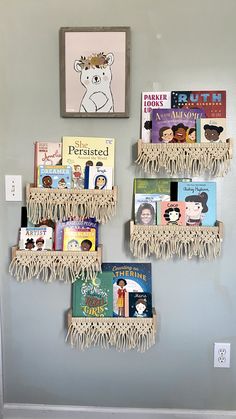 the books are arranged on the wall by the book rack with fringed ends and tassels