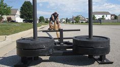 a man standing next to two black tires on the side of a road with houses in the background