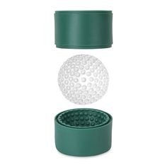 a golf ball sitting on top of a green cup next to a white and black object