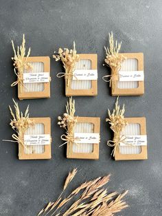 six small square boxes tied with twine and some dried flowers on top of them