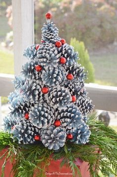 a pine cone christmas tree sitting on top of a potted plant in front of a window