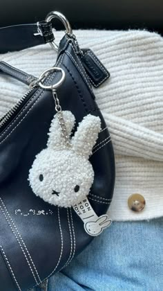 a black purse with a white bunny keychain hanging from it