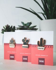 three cards with cactus designs on them sitting next to a potted plant