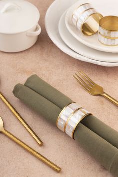 the table is set with gold and green napkins, silverware, and cups