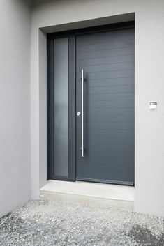 a gray door is open in front of a grey wall and concrete flooring on the side of a building