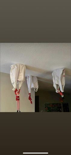 three cloths are hanging from the ceiling with red and white striped stockings on them