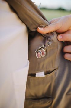 a close up of a person's hand holding onto a jacket with buttons on it