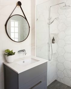 a bathroom with a sink, mirror and shower stall in it that has hexagonal tiles on the walls