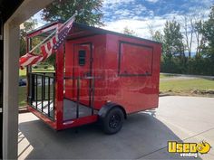 a red trailer parked on the side of a road with an american flag hanging from it's roof