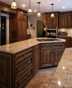 a large kitchen with wooden cabinets and marble counter tops, along with an island in the middle