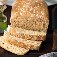 a loaf of bread sitting on top of a wooden cutting board next to a vase with flowers