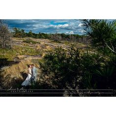 a bride and groom standing in the woods